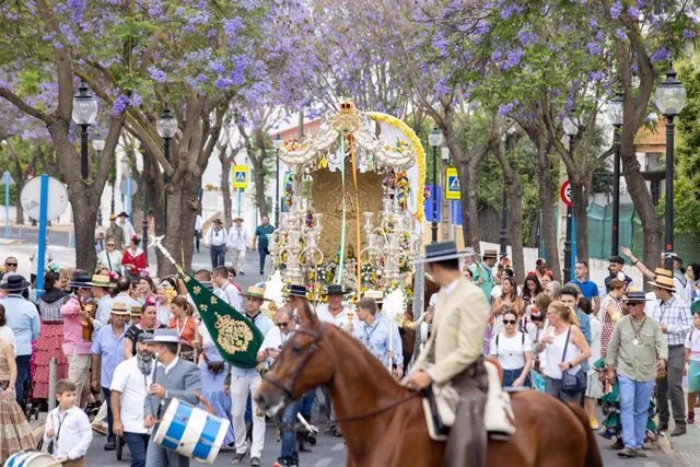 Una imagen que muestra la carreta del Simpecado acompañada por romeros y caballistas, capturando la devoción y el ambiente festivo de la romería.